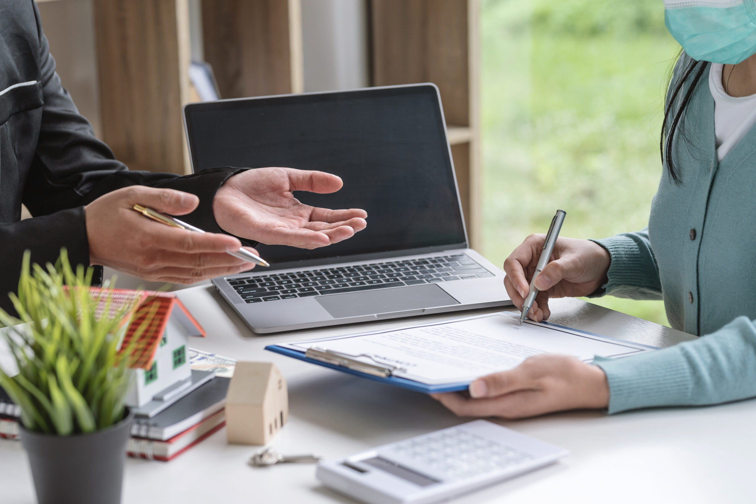 Close-up of customer sign the contract an agreement to sell a house with an agent at the office.