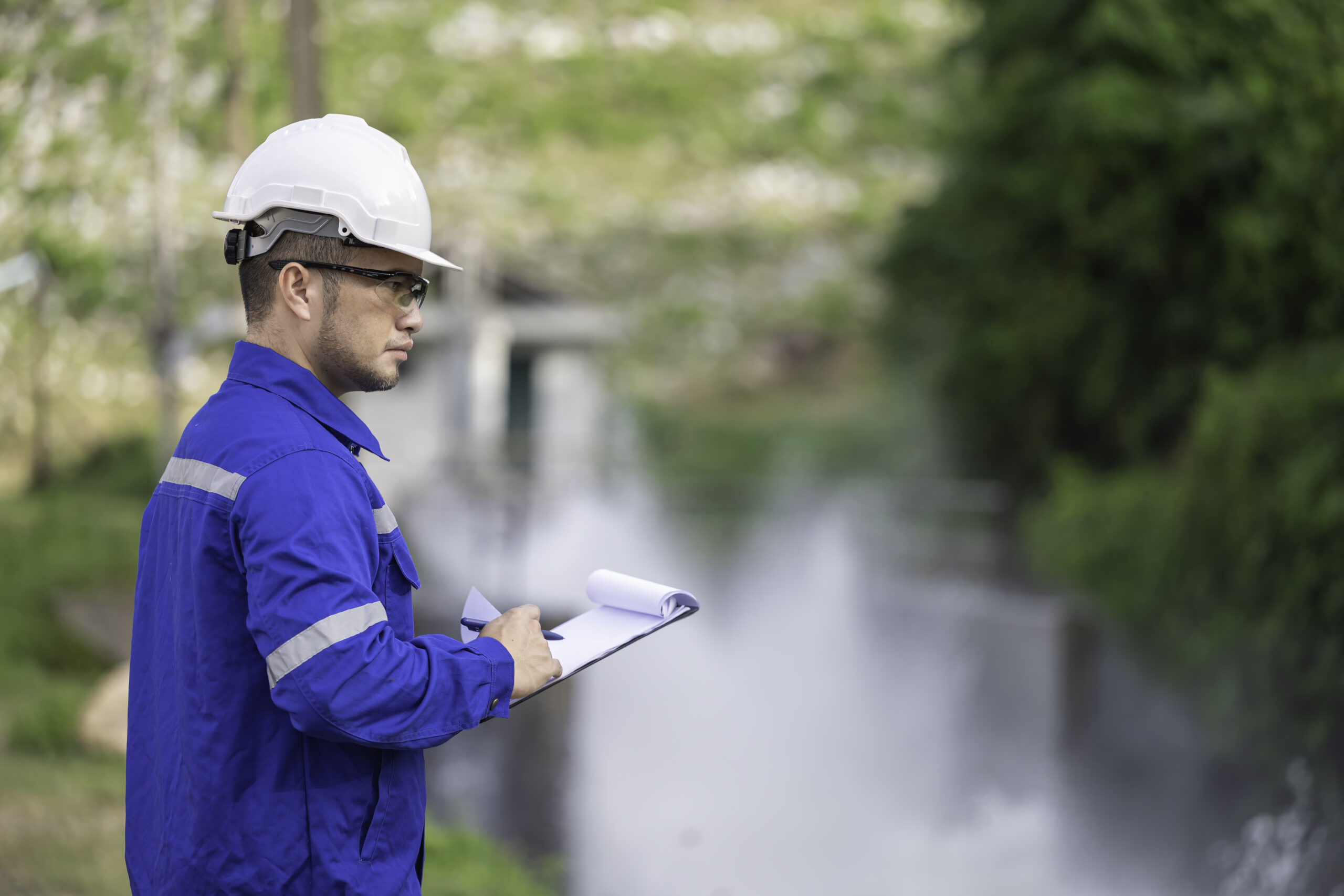 A engineering doing his checking routine. He is wearing hard hat and engineer uniform.Standing by the rail by the dam.Monitor water levels from the heavy rain that has been falling for several days.