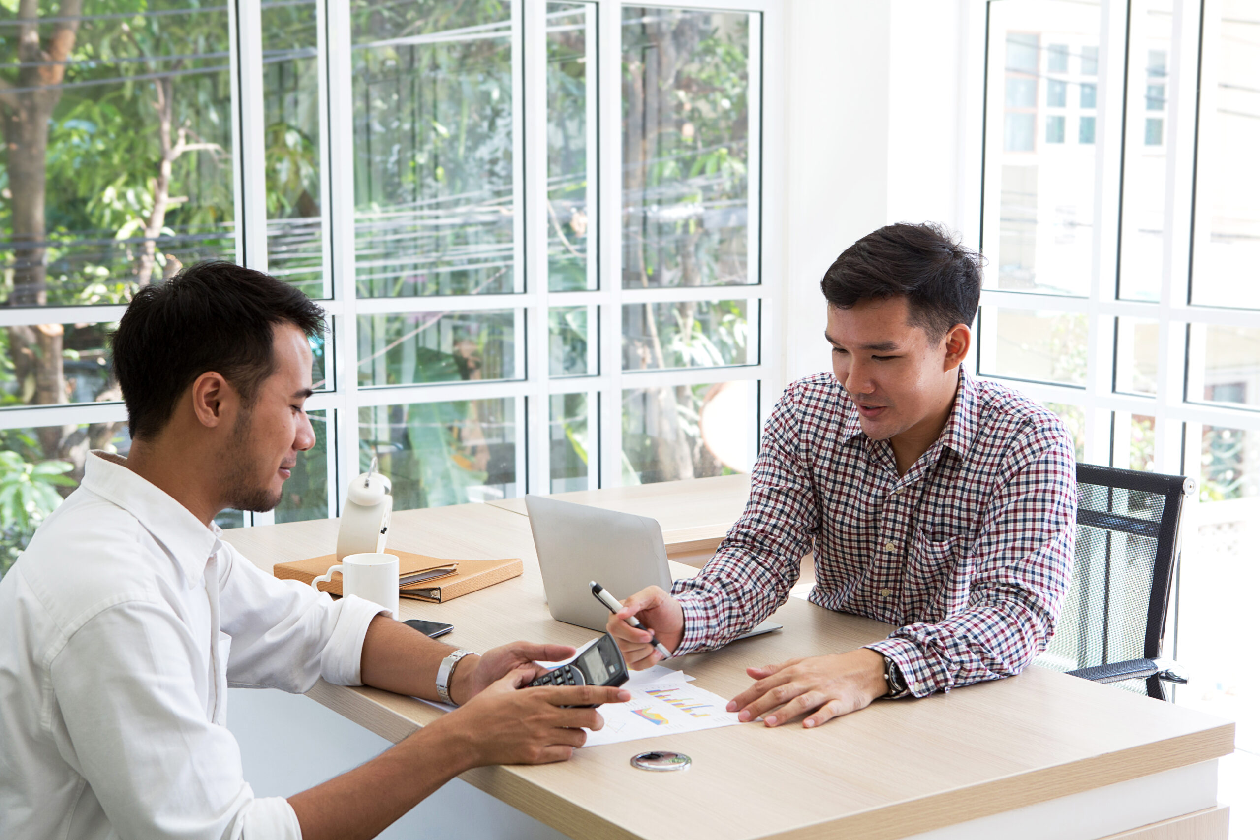 Two businessman plaining data at meeting. Business people meeting around desk. asian people. brainstorming of business. Calculator on the hands of male.