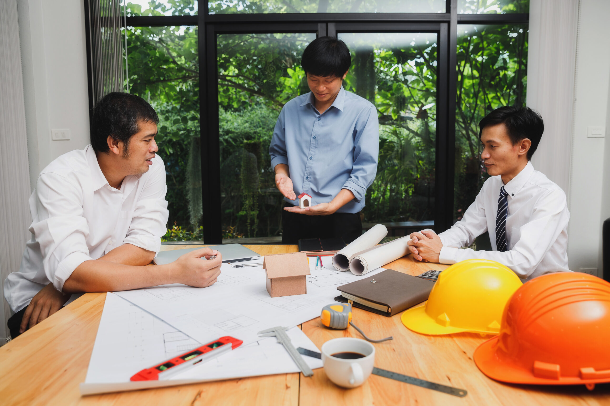 Confident team of architect working together in an office. Then discussing about new startup project on desk. Architect discuss with engineer about project in office.