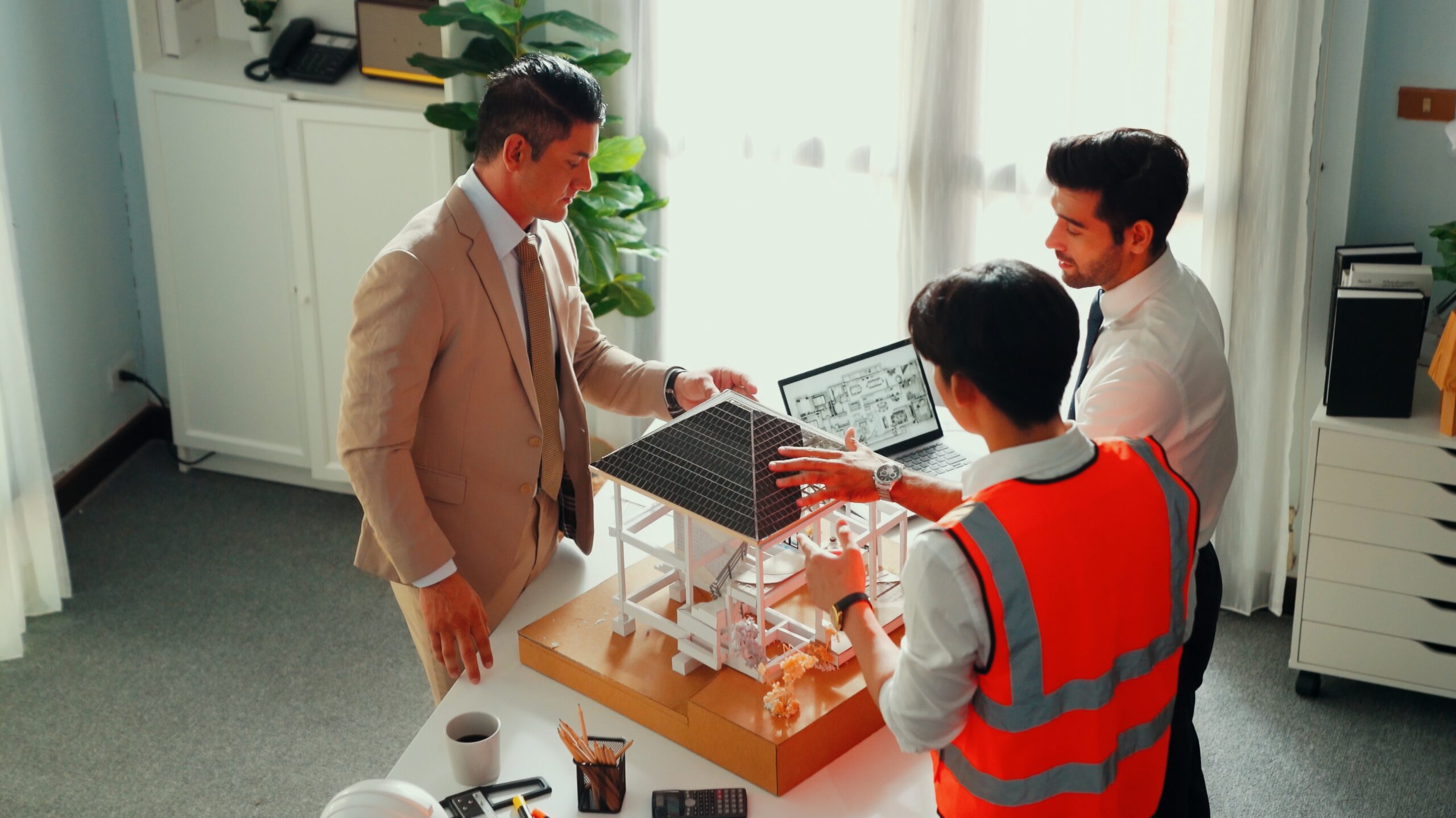 Top view of professional architect engineer team inspect house model while manager holding blueprint and asking about building construction. Group of diverse engineer working together. Alimentation.